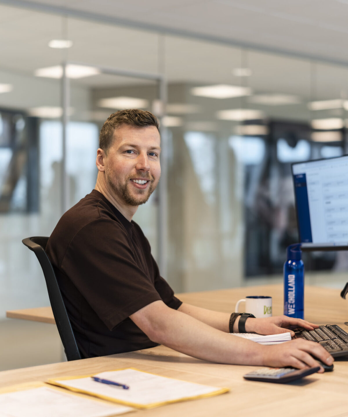 Medewerker van Wex Holland uit team Global lachend van achter zijn bureau in de camera