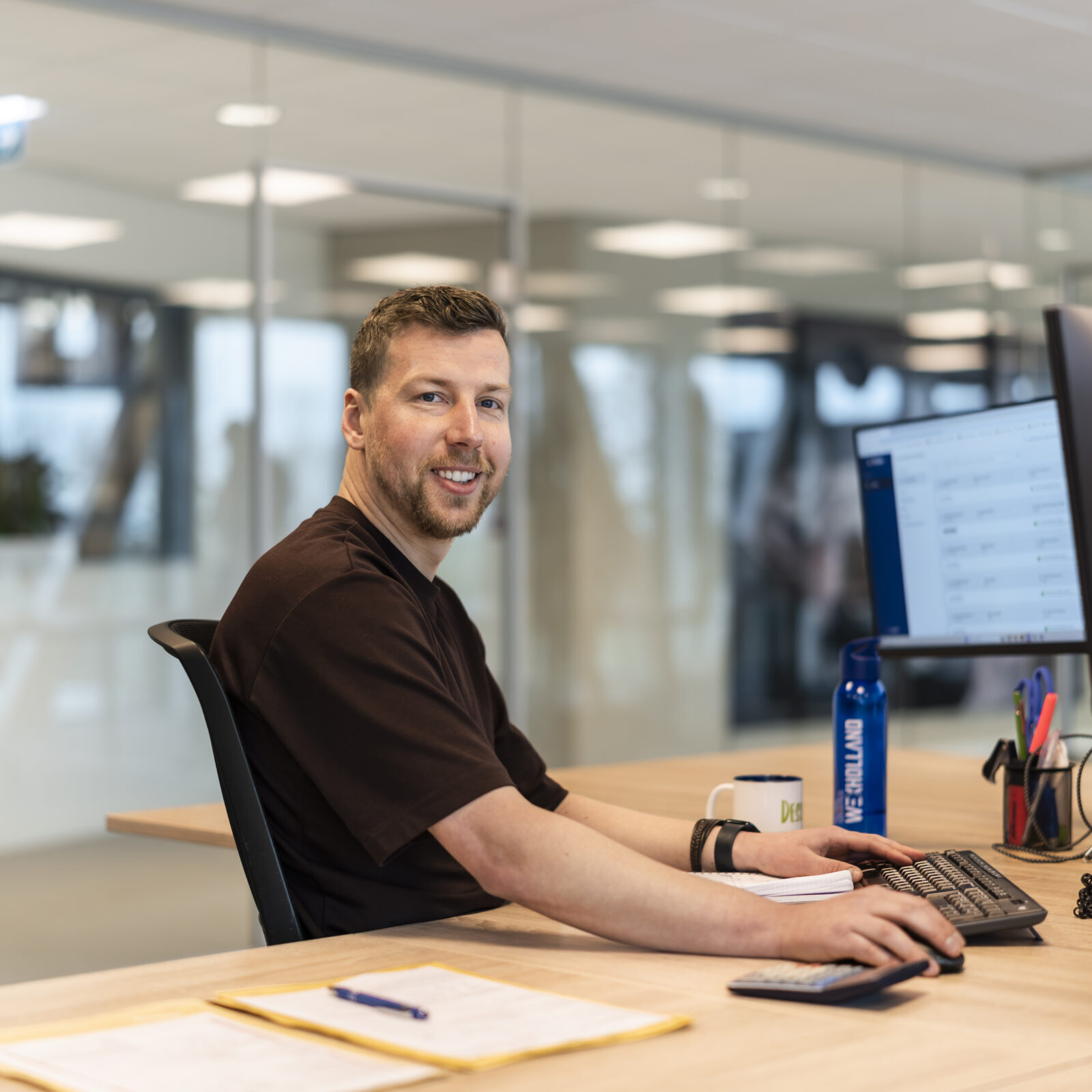 Medewerker van Wex Holland uit team Global lachend van achter zijn bureau in de camera