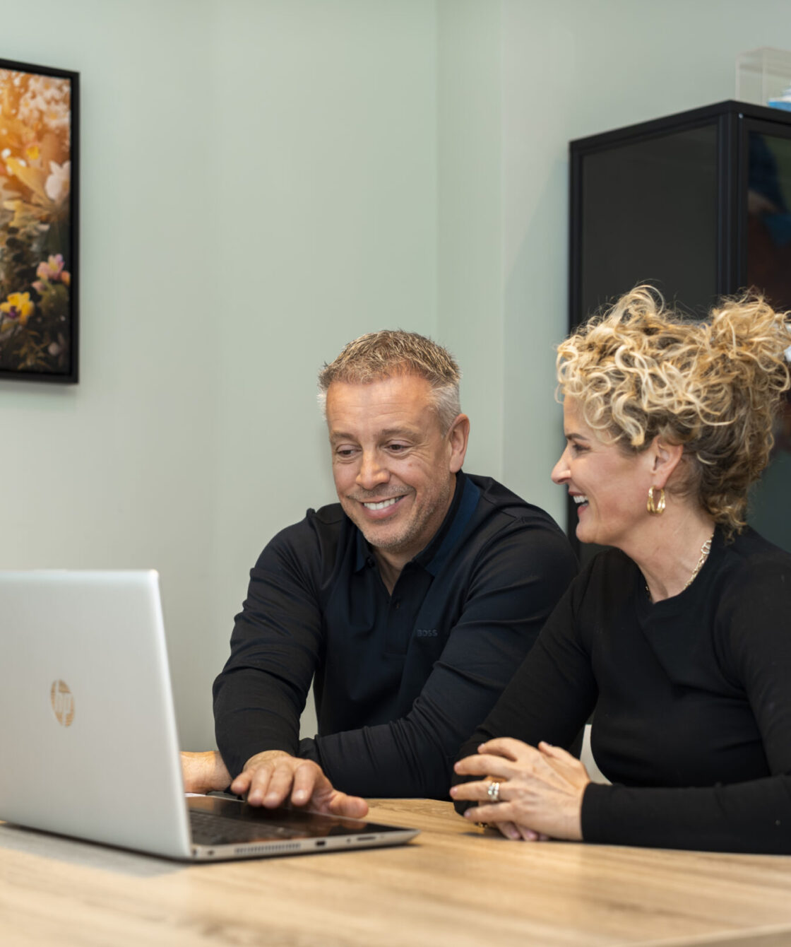 Renzo en Simone Wassink lachend van achter een bureau op het Wex Holland kantoor