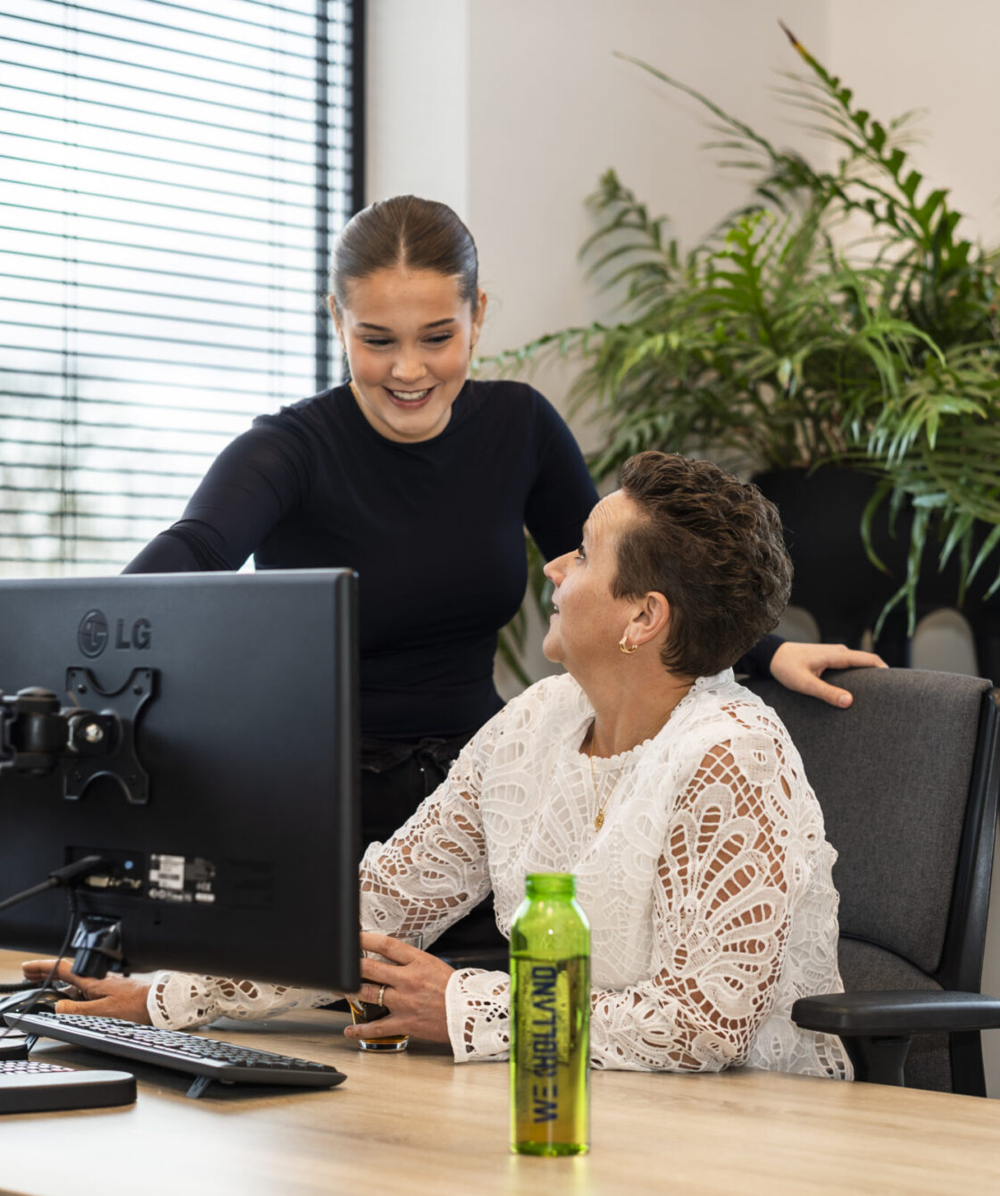 Medewerkers Wex Holland uit afdeling Finance lachend naar elkaar achter een bureau