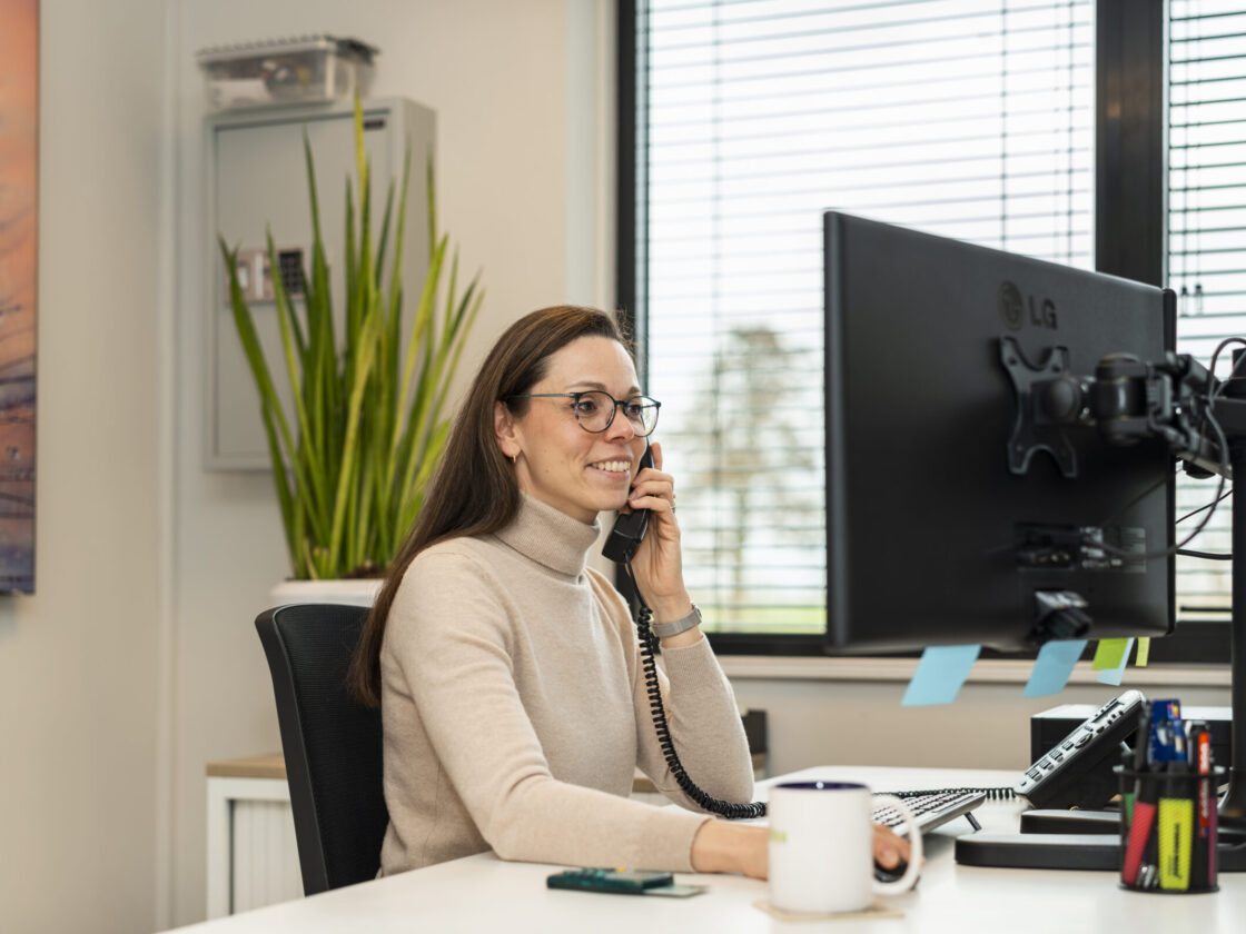 Medewerker Wex Holland van afdeling Finance bellend en lachend van achter een bureau