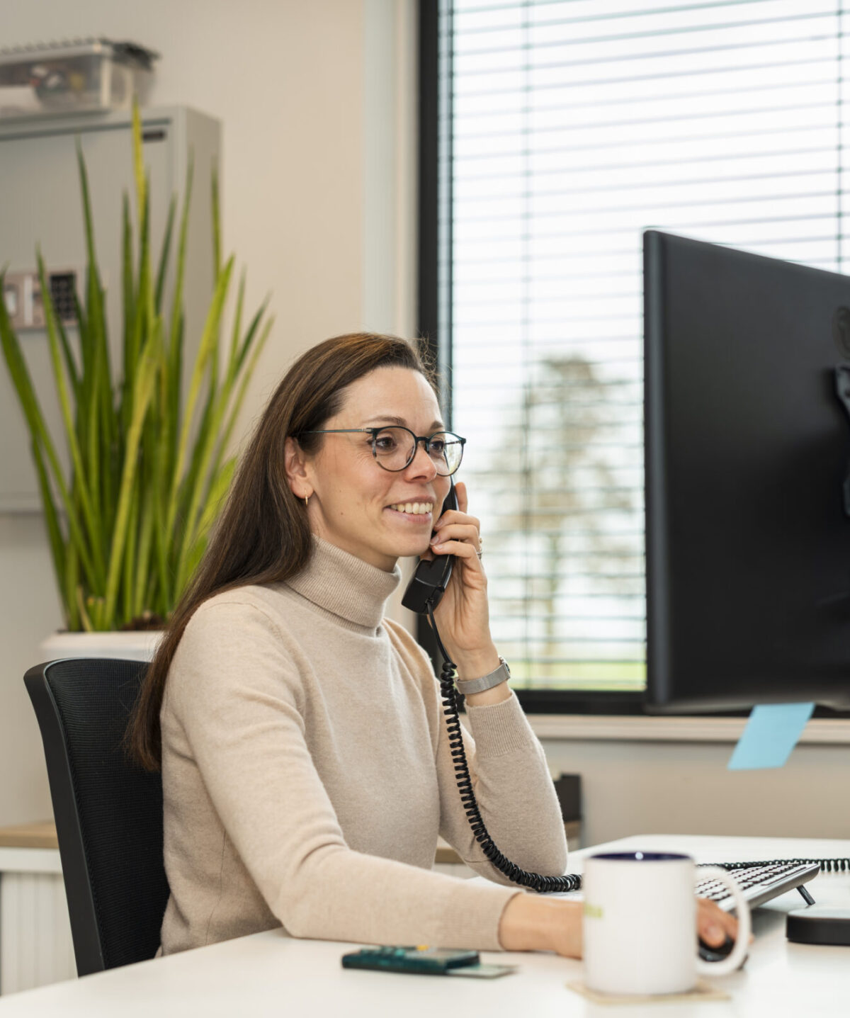 Medewerker Wex Holland van afdeling Finance bellend en lachend van achter een bureau