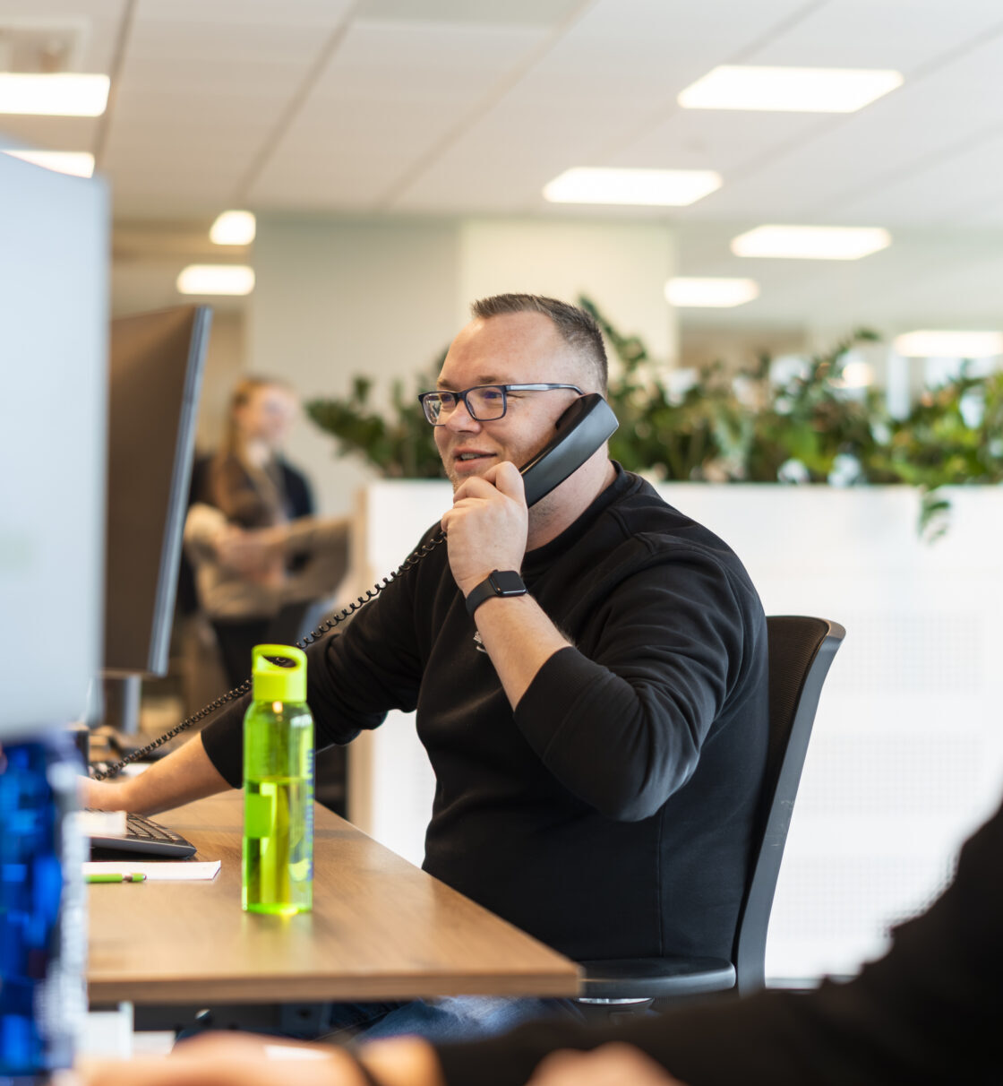 Wex Holland medewerker transportplanner lachend en bellend van achter een bureau