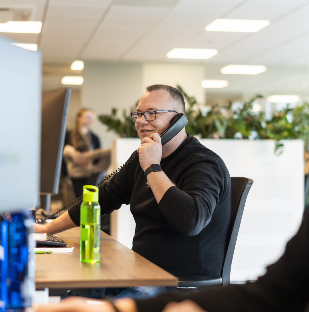 Wex Holland medewerker transportplanner lachend en bellend van achter een bureau