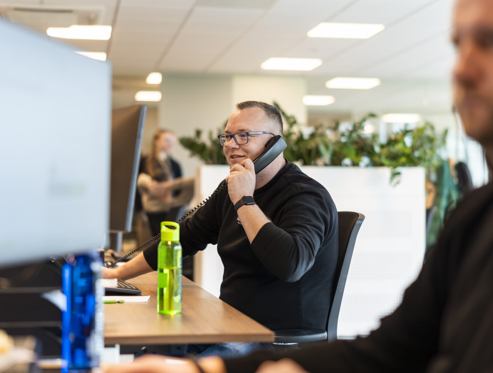 Wex Holland medewerker transportplanner lachend en bellend van achter een bureau