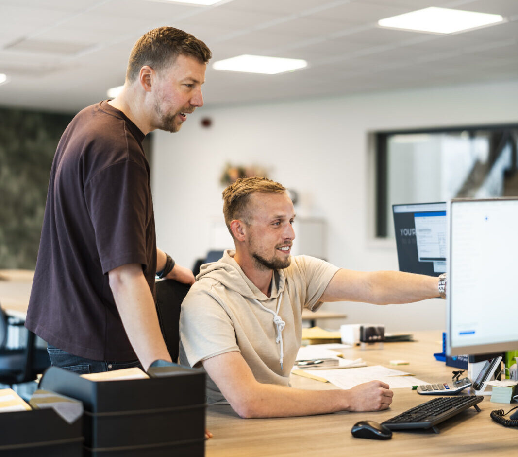 Medewerkers van Wex Holland uit Team Global achter een bureau kijkend op een beeldscherm