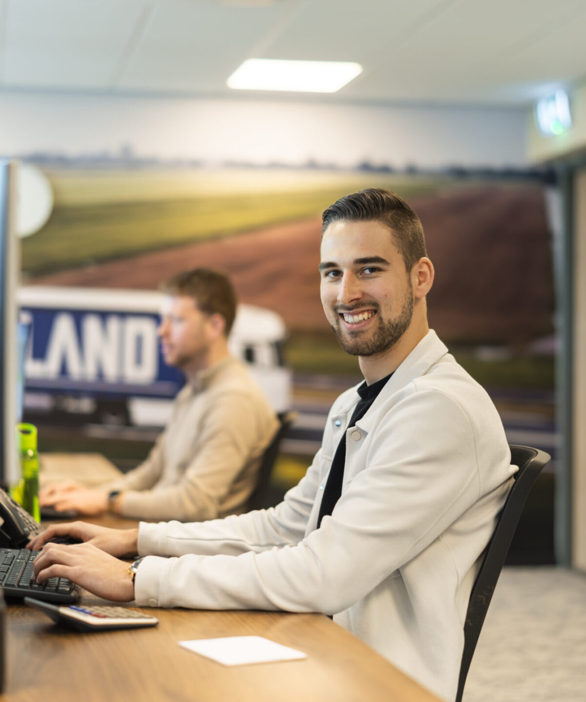 Medewerker Wex Holland transportplanner achter zijn bureau lachend naar de camera