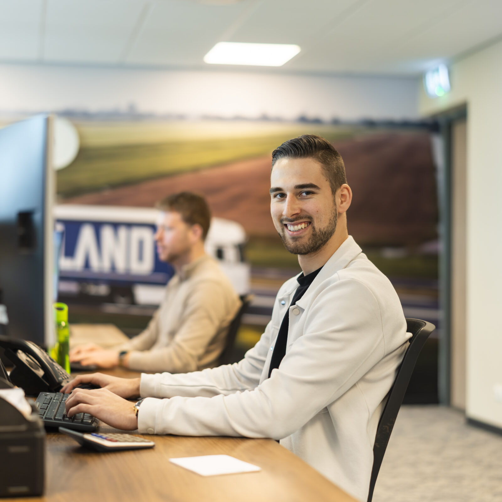 Medewerker Wex Holland transportplanner achter zijn bureau lachend naar de camera