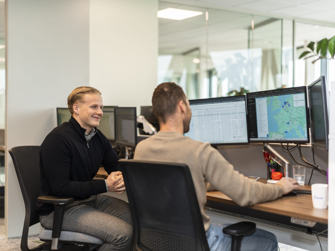 Wex Holland medewerkers transportplanners kijkend en lachend naar een planbord